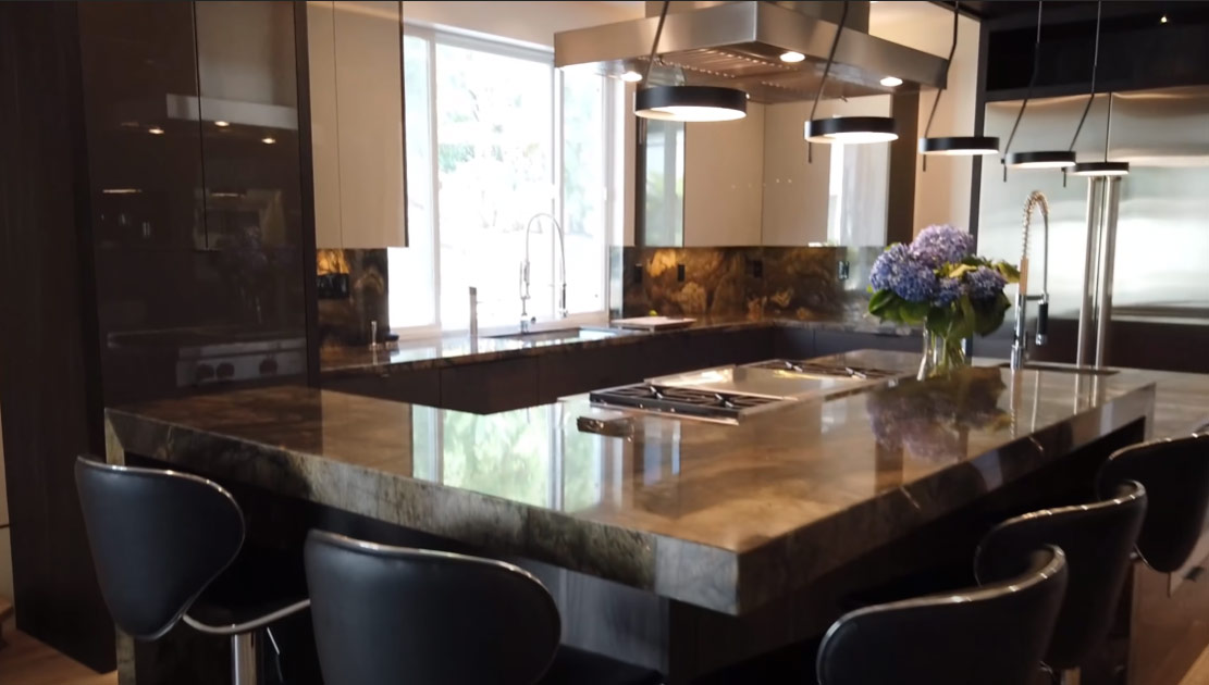 Granite island style kitchen with lighting fixtures and bar stools
